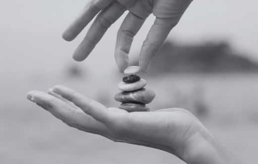 Hands stacking rocks