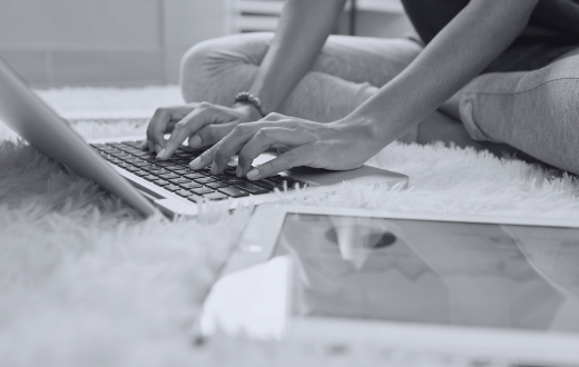 A woman sits on the floor with her laptop, entering data