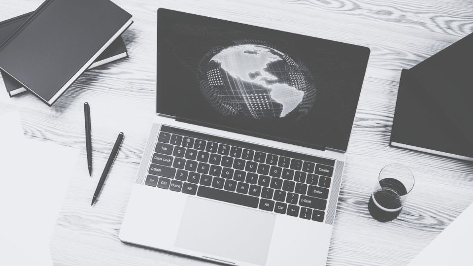 A laptop sitting on a desk with a photo of the earth on the screen.