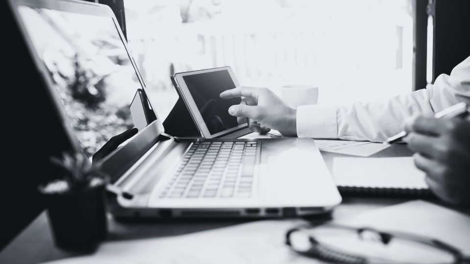 A Support tech looks at his laptop and ticketing screen, technical support concept.